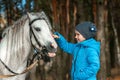 Little girl portrait, stands next to a white pony close-up on the background of nature. Jockey, epodrome, horseback riding Royalty Free Stock Photo