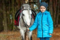 Little girl portrait, stands next to a white pony close-up on the background of nature. Jockey, epodrome, horseback riding Royalty Free Stock Photo