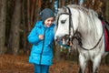 Little girl portrait, stands next to a white pony close-up on the background of nature. Jockey, epodrome, horseback riding Royalty Free Stock Photo