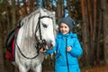 Little girl portrait, stands next to a white pony close-up on the background of nature. Jockey, epodrome, horseback riding Royalty Free Stock Photo