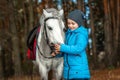 Little girl portrait, stands next to a white pony close-up on the background of nature. Jockey, epodrome, horseback riding Royalty Free Stock Photo