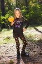 Little girl posing in autumn forest. Cheerful child and pumpkin at park
