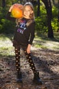 Little girl posing in autumn forest. Funny kid in carnival costume at Halloween trick or treat