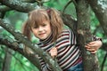 Little girl posing sitting on a tree in the garden in the village. Royalty Free Stock Photo