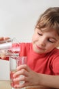 Little girl pour out water from one glass to other