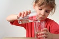 Little girl pour out water from one glass to other