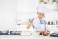 Little girl pouring flour into a bowl in kitchen