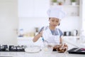 Little girl pouring flour into chocolate dough