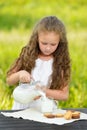 Little girl pouring milk in glass outdoor summer Royalty Free Stock Photo