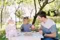 Little girl pours tea from a toy teapot into a toy cup in her daddy hand at a tea party in the garden Royalty Free Stock Photo