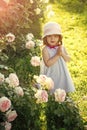 Little girl praying to god. Child standing at blossoming rose flowers on green grass Royalty Free Stock Photo