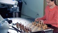 Little girl preparaing chessboard for playing chess with a robot.