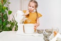 little girl prepares dough or cream in a submersible mixer and licks his fingers