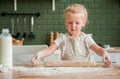 Little girl prepares dough in the kitchen. Rolls the dough with a rolling pin