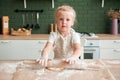 Little girl prepares dough in the kitchen. Rolls the dough with a rolling pin