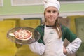 Little girl preparing homemade pizza. Beautiful little girl in a chef attire with a pizza in her hands Royalty Free Stock Photo