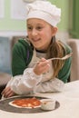 Little girl preparing homemade pizza. Beautiful little girl in a chef attire with a pizza in her hands. vertical photo Royalty Free Stock Photo