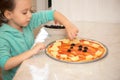 Little girl preparing homemade pizza in the kitchen