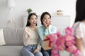 Little girl presenting mother and granny with gift and spring flowers, congratulating family with Women& x27;s Day at home