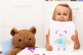 Little girl presents her drawing - a portrait of her toy bear