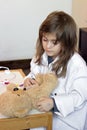 Little girl pretends to be a doctor and playing with her teddy b