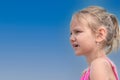 Little girl in profile with blond hair, 6-7 years old, against a blue sky Royalty Free Stock Photo