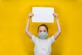 Little girl in a protective mask holds a blank sheet of paper over her. Protection against coronavirus Royalty Free Stock Photo