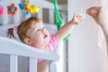 Little girl pulls her hand to the dummy, standing in a baby crib Royalty Free Stock Photo