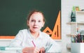 Little girl pupil with happy face expression near desk with school supplies. Learning concept. Happy school kids at Royalty Free Stock Photo