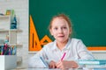 Little girl pupil with happy face expression near desk with school supplies. Learning concept. Happy school kids at Royalty Free Stock Photo