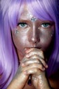A little girl in a purple wig with silver sequins on her face. An alien, fantasy world.A fairy or an alien.