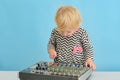 A little girl pushes buttons on a music mixing console