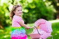 Little girl pushing a toy stoller wth doll Royalty Free Stock Photo