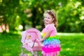 Little girl pushing a toy stroller wth doll Royalty Free Stock Photo