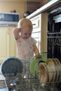 Little girl puts a plate in the dishwasher Royalty Free Stock Photo