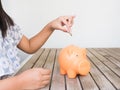 Little girl putting coin into piggy bank for saving with pile of Royalty Free Stock Photo