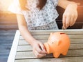 Little girl putting coin into piggy bank for saving with pile of Royalty Free Stock Photo