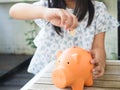 Little girl putting coin into piggy bank for saving with pile of Royalty Free Stock Photo