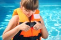 Little girl putting on orange life vest in swimming pool Royalty Free Stock Photo