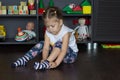 Little girl putting on socks sitting on floor indoor
