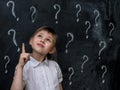 Little girl with question marks on blackboard. Concept for confusion, brainstorming and choice. Royalty Free Stock Photo