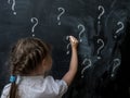 Little girl with question marks on blackboard. Concept for confusion, brainstorming and choice. Royalty Free Stock Photo