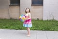 Little girl in rainbow coloured dress and bare feet holding clear vinyl beach ball