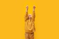 Little girl raised hands up and points index fingers up. Copy space, mock up. Vertical frame, child in yellow clothes Royalty Free Stock Photo