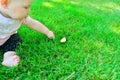 A little girl reaches for a leaf lying on the green grass Royalty Free Stock Photo