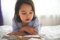 Little girl reading from bible while she is in bed in the morning Royalty Free Stock Photo