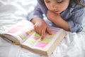 Little girl reading from Bible while lying in bed. Fetita citind din biblie in timp ce sta intinsa in pat Royalty Free Stock Photo