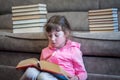 A little girl is reading a big, fat book in her lap. Serious child is studying a textbook. Children`s educational concept Royalty Free Stock Photo