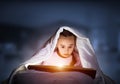 Little girl reading book in bed Royalty Free Stock Photo