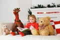 Little girl reading a book in his toys Christmas decorations